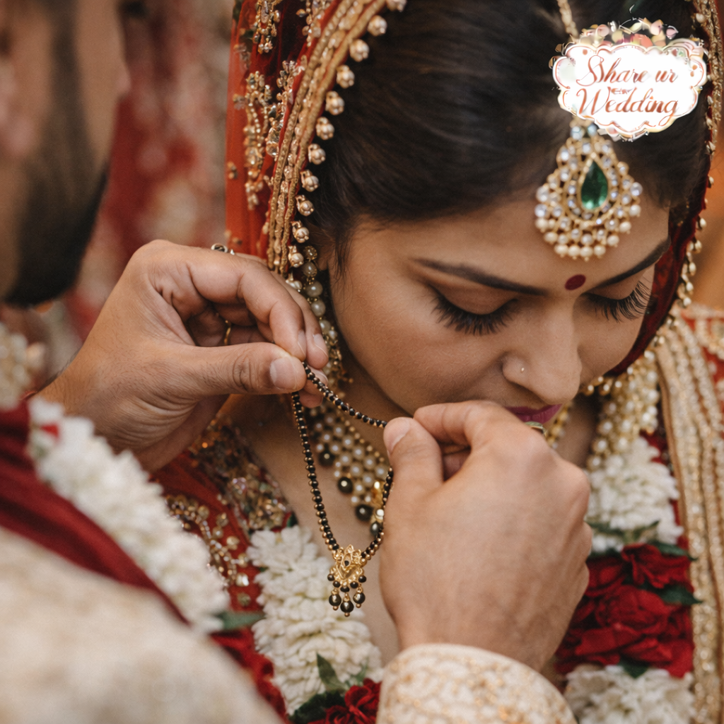 Indian wedding mangalsutra tying close-up with groom tying sacred necklace on bride during Hindu ceremony